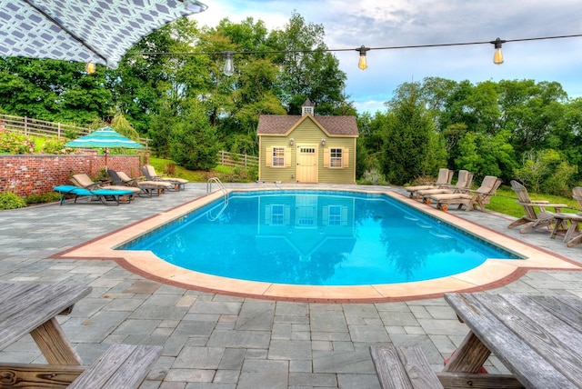 view of swimming pool featuring an outbuilding and a patio