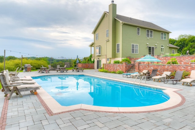 view of pool featuring area for grilling and a patio area