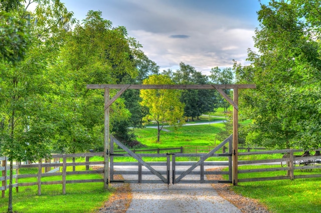 view of gate with a rural view and a lawn