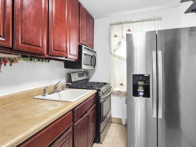 kitchen with appliances with stainless steel finishes, sink, and light tile patterned floors