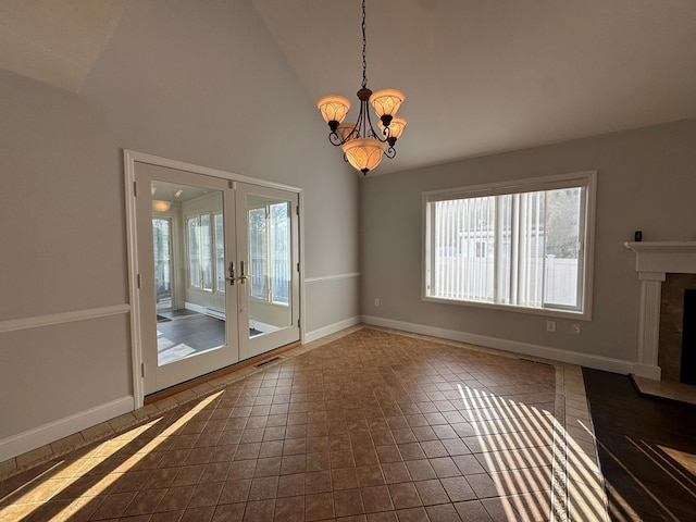 unfurnished dining area featuring dark tile patterned flooring, a notable chandelier, high vaulted ceiling, and french doors