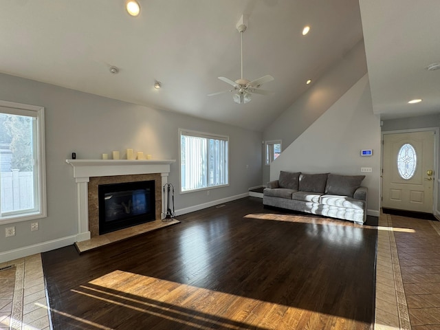 living room with a tile fireplace, vaulted ceiling, ceiling fan, and dark hardwood / wood-style floors