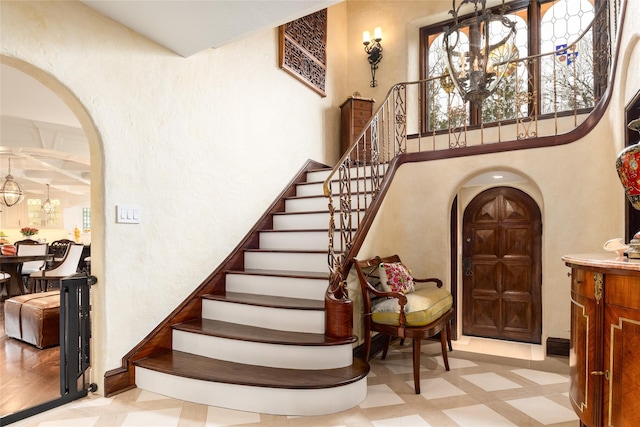 stairs with a towering ceiling and a notable chandelier