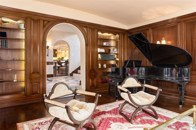 living area featuring built in shelves, wooden walls, dark hardwood / wood-style flooring, and vaulted ceiling