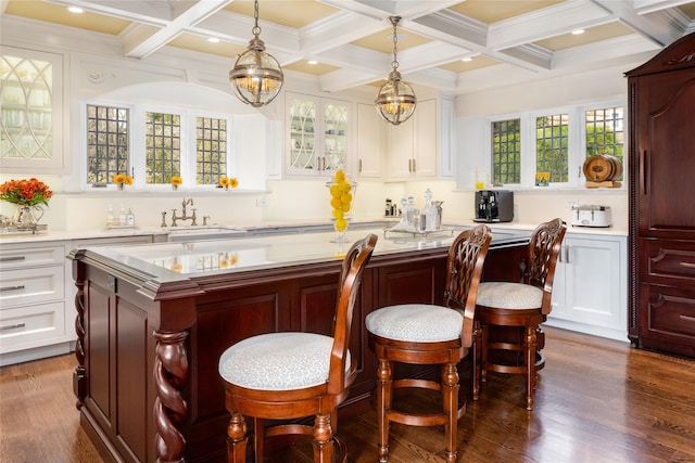 interior space featuring pendant lighting, sink, white cabinetry, and a center island