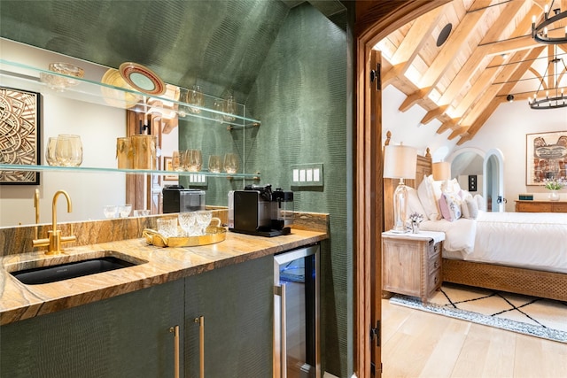 bar with wine cooler, sink, vaulted ceiling with beams, wood-type flooring, and light stone countertops