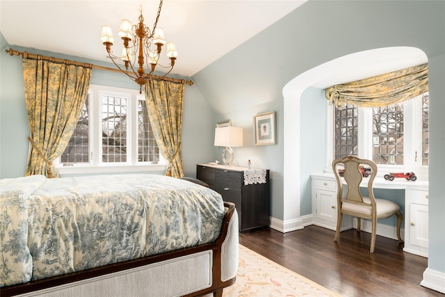 bedroom with an inviting chandelier, dark hardwood / wood-style flooring, built in desk, and vaulted ceiling