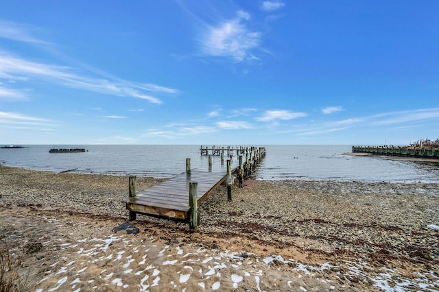 view of dock with a water view and a beach view