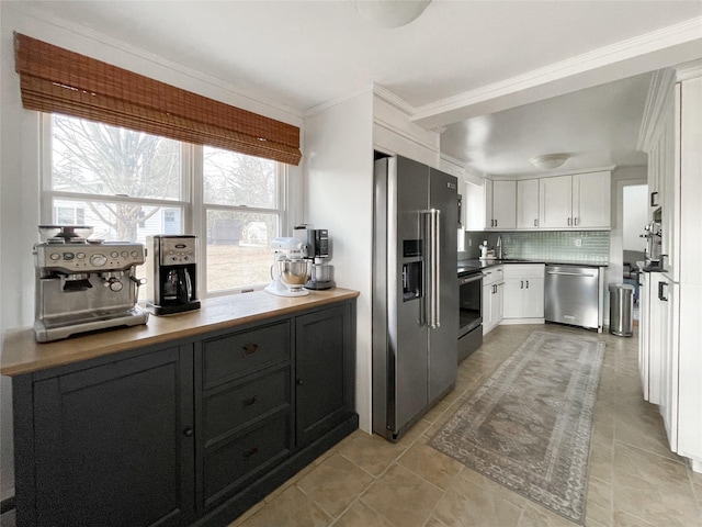 kitchen featuring sink, white cabinetry, crown molding, stainless steel appliances, and decorative backsplash