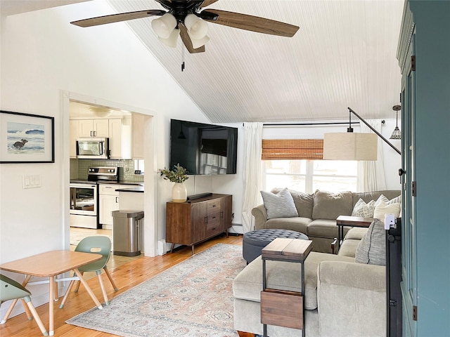 living room with vaulted ceiling, ceiling fan, and light wood-type flooring