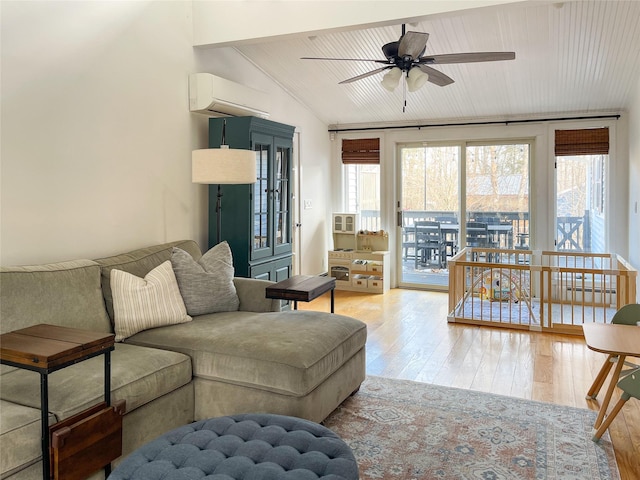 living room with lofted ceiling, a healthy amount of sunlight, a wall unit AC, and light hardwood / wood-style flooring