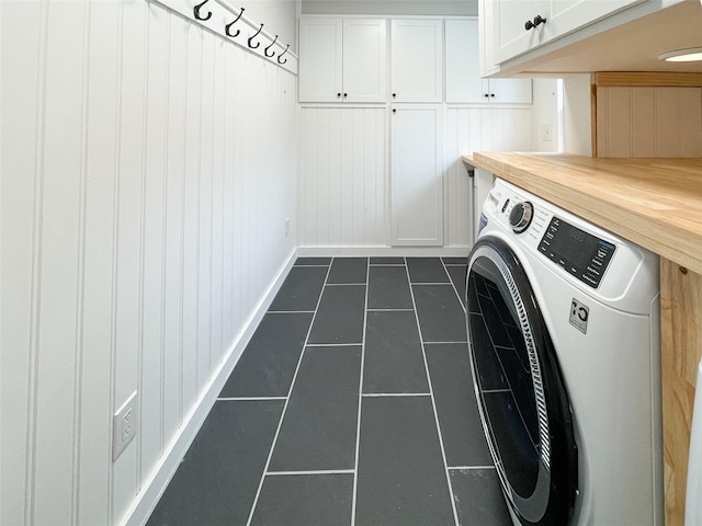 laundry area featuring cabinets, washer / dryer, and dark tile patterned flooring