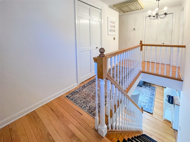 stairs with wood-type flooring and a chandelier