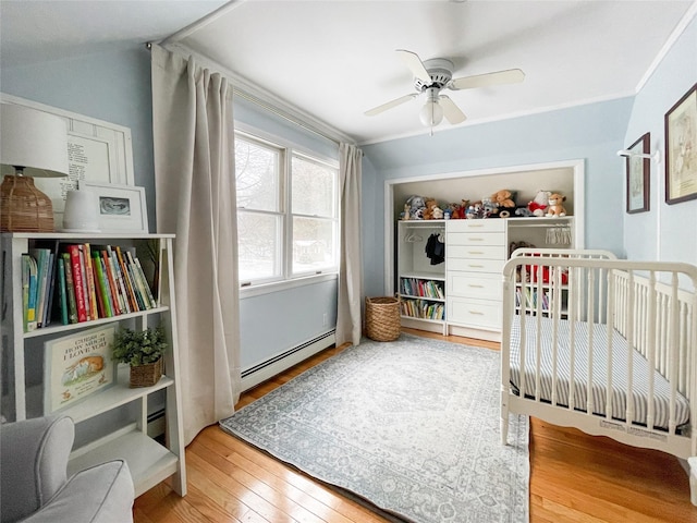 bedroom featuring a baseboard radiator, wood-type flooring, and ceiling fan