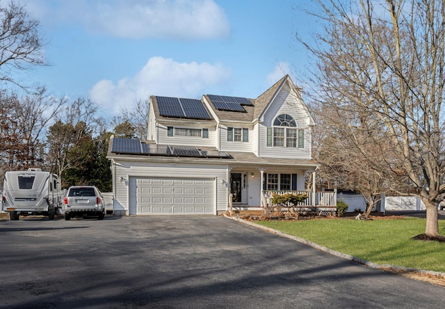 view of front facade featuring a porch, a garage, a front yard, and solar panels