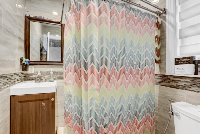 bathroom featuring vanity, a shower, tile walls, and toilet