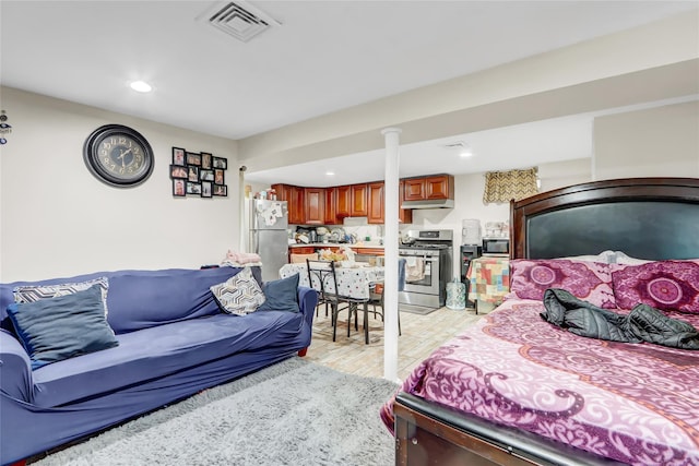 bedroom featuring stainless steel fridge and light hardwood / wood-style floors