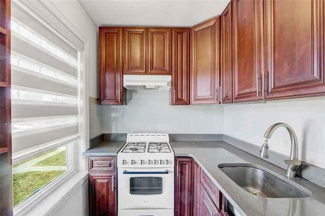 kitchen with white gas stove, sink, and light stone countertops