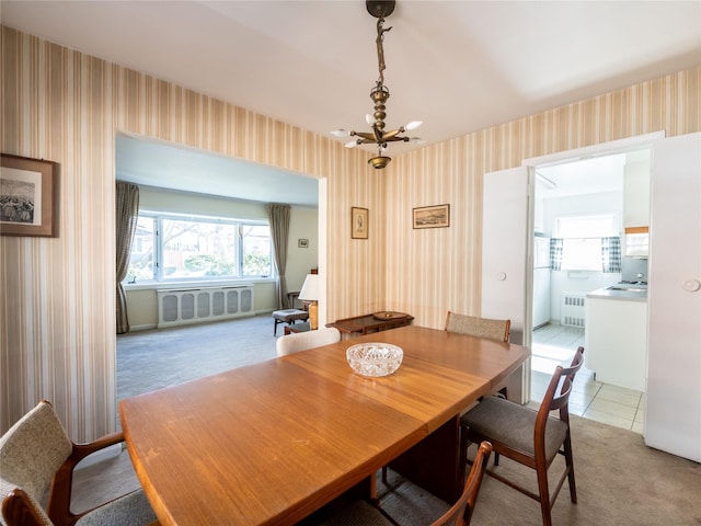 carpeted dining space with a chandelier and radiator