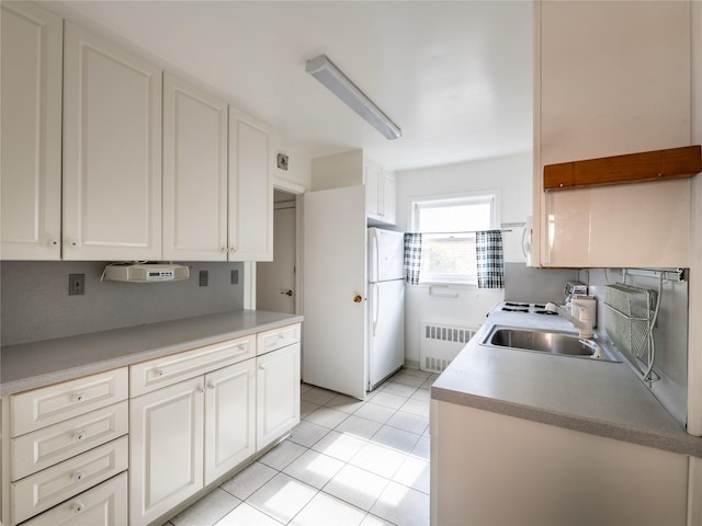 kitchen featuring light tile patterned flooring, radiator, sink, white cabinets, and white refrigerator