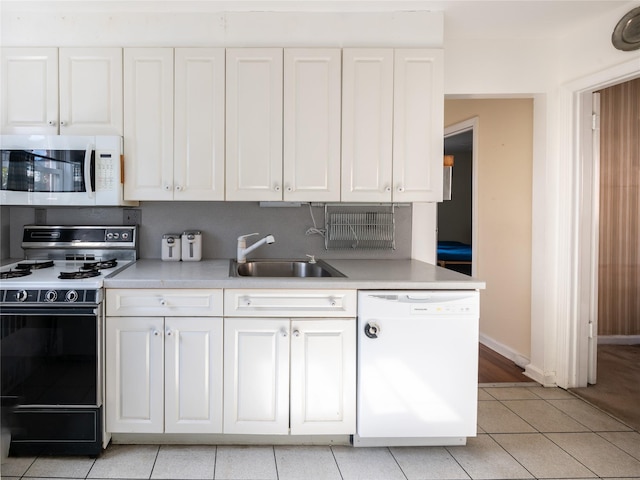 kitchen featuring sink, white appliances, light tile patterned floors, tasteful backsplash, and white cabinets