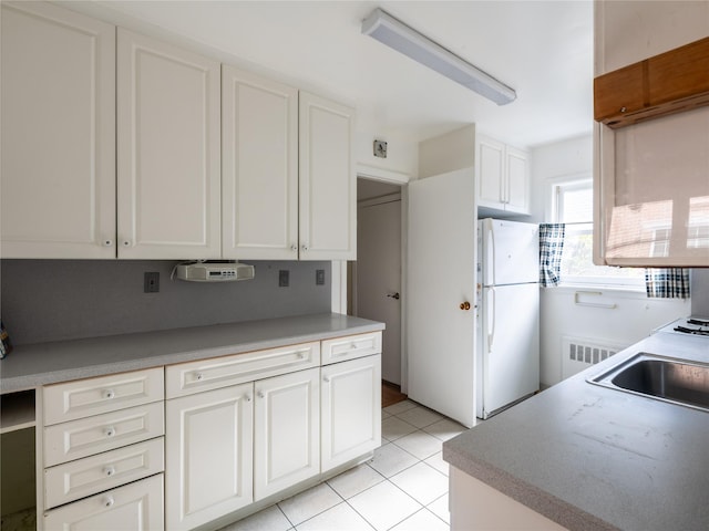 kitchen featuring white cabinetry, white fridge, sink, and light tile patterned floors