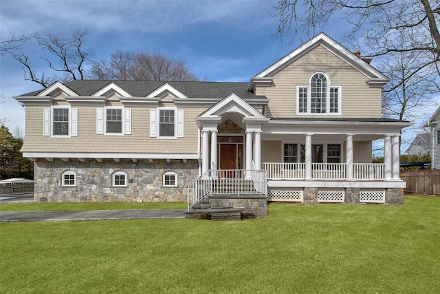 view of front of home featuring stone siding, covered porch, roof with shingles, and a front lawn