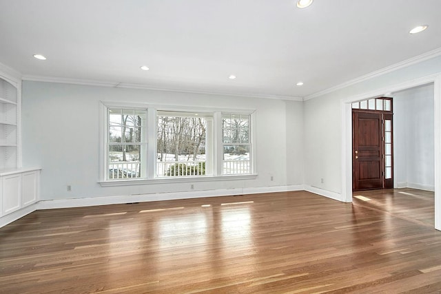 spare room featuring dark wood-type flooring, recessed lighting, crown molding, and baseboards