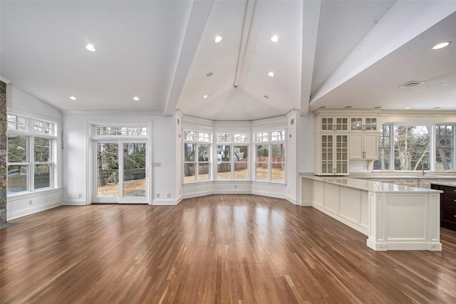 unfurnished living room with dark wood-style flooring, visible vents, plenty of natural light, and lofted ceiling with beams