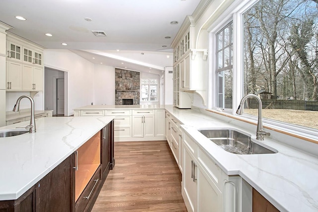 kitchen featuring glass insert cabinets, a sink, and light stone countertops