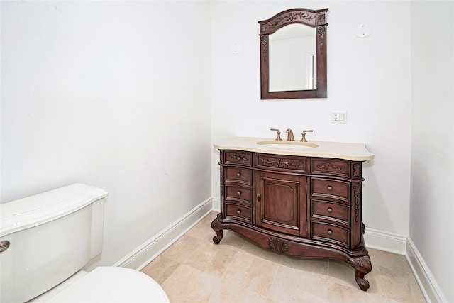 bathroom with baseboards, vanity, and toilet