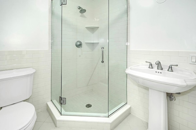 bathroom with a shower stall, tile walls, and toilet