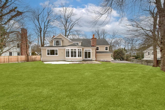 back of house with a yard, fence, and a chimney