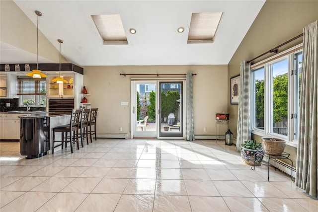 kitchen featuring lofted ceiling, a breakfast bar, light tile patterned floors, pendant lighting, and a baseboard heating unit