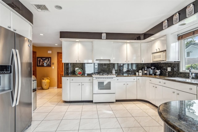 kitchen featuring dark stone countertops, sink, white appliances, and white cabinets