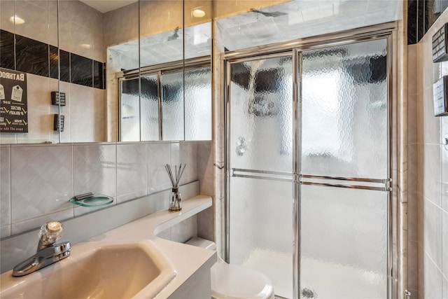 bathroom featuring a shower with door, vanity, tile walls, and backsplash