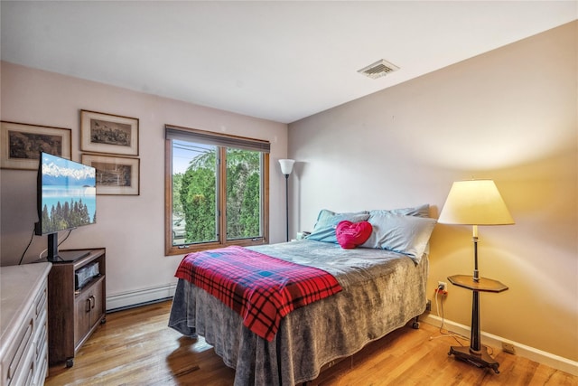 bedroom featuring a baseboard radiator and light hardwood / wood-style flooring