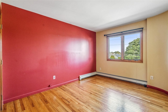 spare room with a baseboard radiator and light wood-type flooring