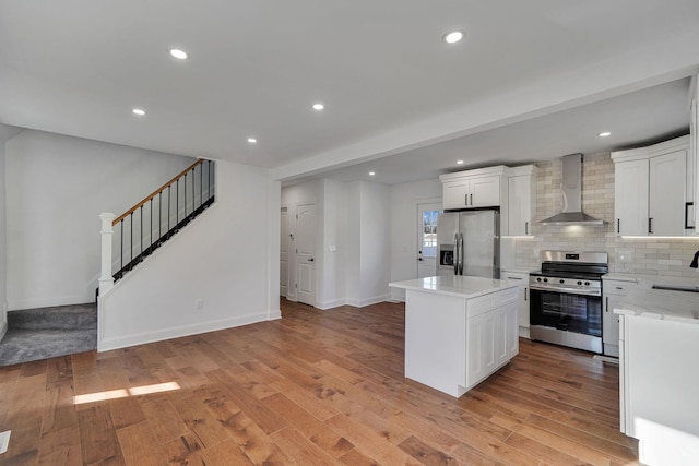 kitchen with white cabinetry, a center island, wall chimney exhaust hood, and appliances with stainless steel finishes