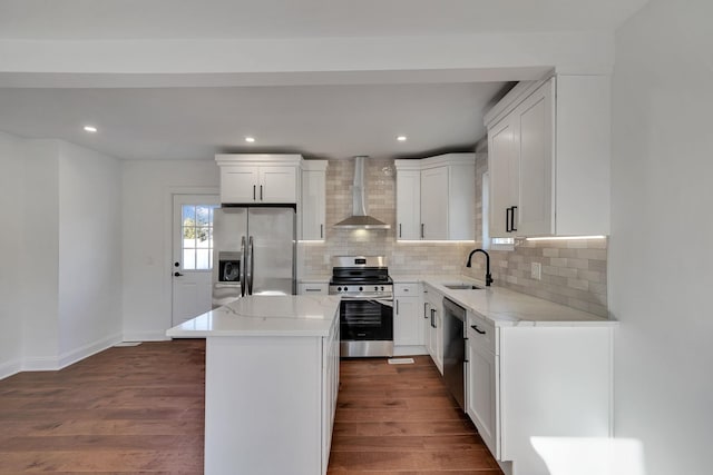 kitchen featuring a kitchen island, white cabinetry, sink, stainless steel appliances, and wall chimney range hood