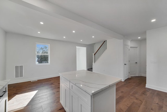 kitchen with white cabinetry, a kitchen island, dark hardwood / wood-style flooring, and light stone counters