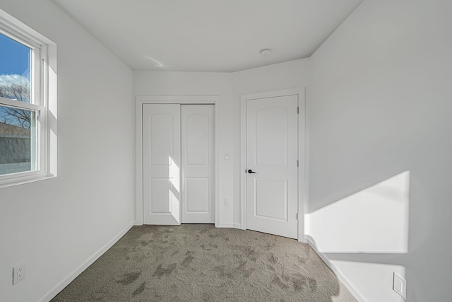 unfurnished bedroom featuring light carpet and a closet