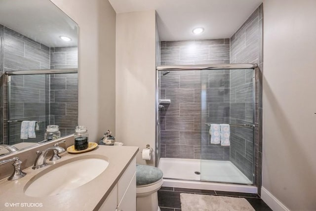 bathroom featuring vanity, a shower with door, and toilet