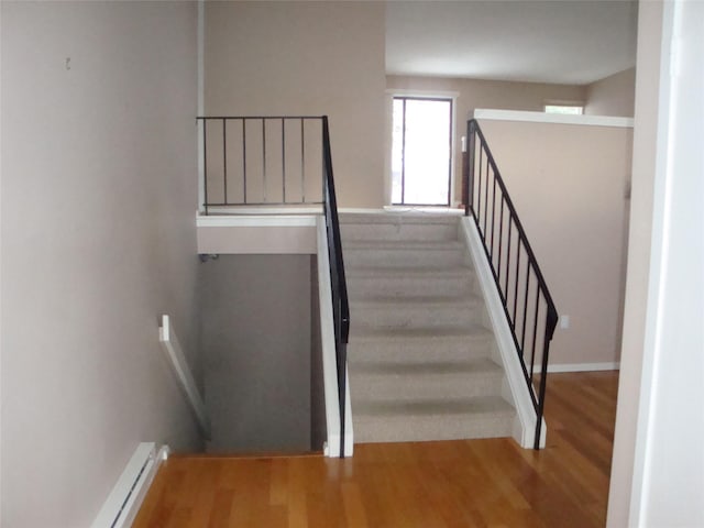 staircase with hardwood / wood-style flooring and a baseboard heating unit