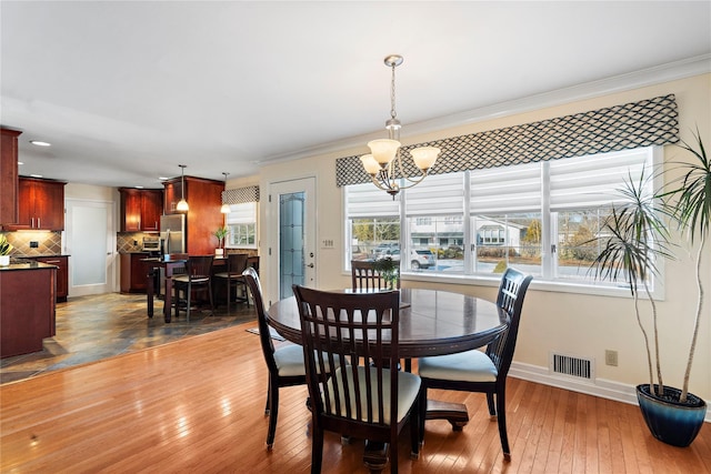 dining space with crown molding, a chandelier, and hardwood / wood-style floors