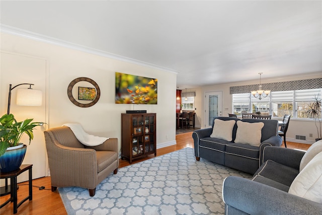 living room with hardwood / wood-style flooring, crown molding, and a notable chandelier