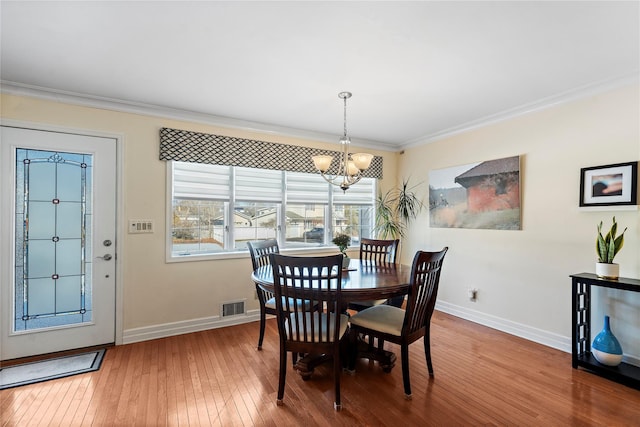 dining area with hardwood / wood-style floors, a notable chandelier, and ornamental molding