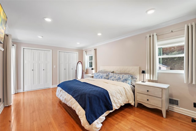 bedroom with crown molding, multiple closets, and light wood-type flooring