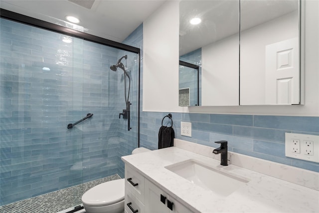 bathroom with vanity, toilet, a shower with shower door, and tile walls