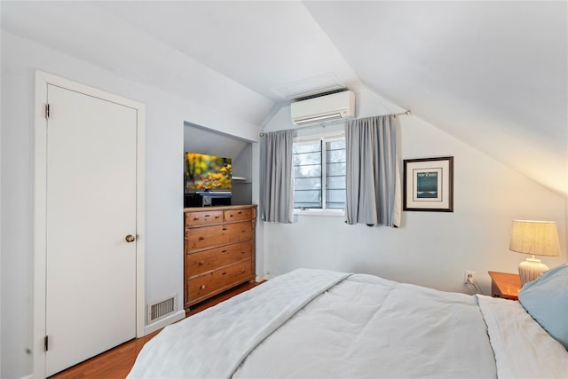 bedroom with wood-type flooring, lofted ceiling, and a wall mounted air conditioner